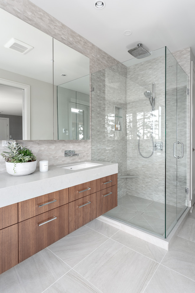 Photo of a large beach style master bathroom in Vancouver with flat-panel cabinets, blue cabinets, a drop-in tub, an alcove shower, a two-piece toilet, gray tile, ceramic tile, grey walls, porcelain floors, an undermount sink, engineered quartz benchtops, grey floor, a hinged shower door, grey benchtops, a double vanity and a floating vanity.