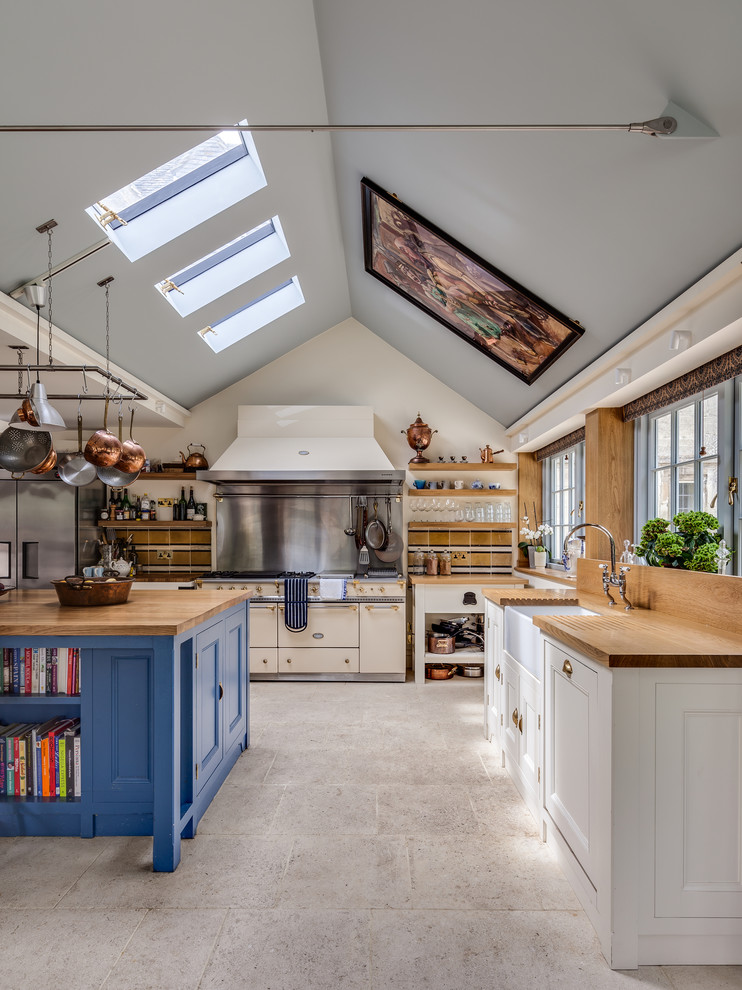 Country l-shaped eat-in kitchen in Gloucestershire with shaker cabinets, wood benchtops and with island.