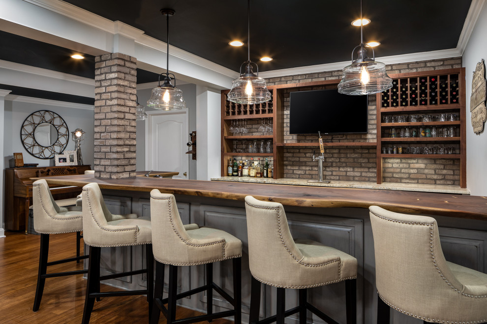 Traditional seated home bar in DC Metro with open cabinets, dark wood cabinets, brick splashback, medium hardwood floors and beige benchtop.