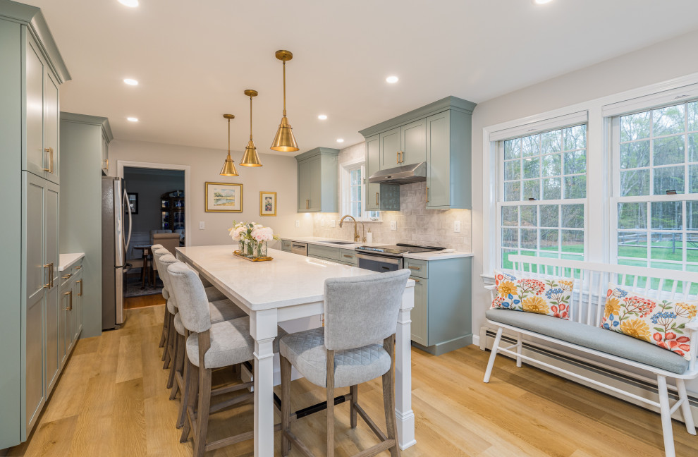Inspiration for a transitional galley medium tone wood floor and brown floor kitchen remodel with an undermount sink, shaker cabinets, green cabinets, gray backsplash, stainless steel appliances, an island and white countertops