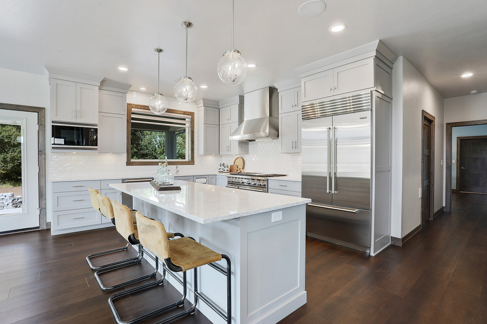Mid-sized transitional u-shaped vinyl floor and brown floor open concept kitchen photo with gray walls, an undermount sink, flat-panel cabinets, gray cabinets, quartz countertops, white backsplash, porcelain backsplash, stainless steel appliances, an island and white countertops