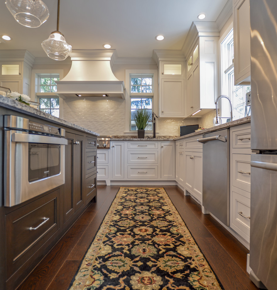 Inspiration for a transitional dark wood floor and brown floor eat-in kitchen remodel with an undermount sink, shaker cabinets, white cabinets, granite countertops, white backsplash, ceramic backsplash, stainless steel appliances, an island and beige countertops