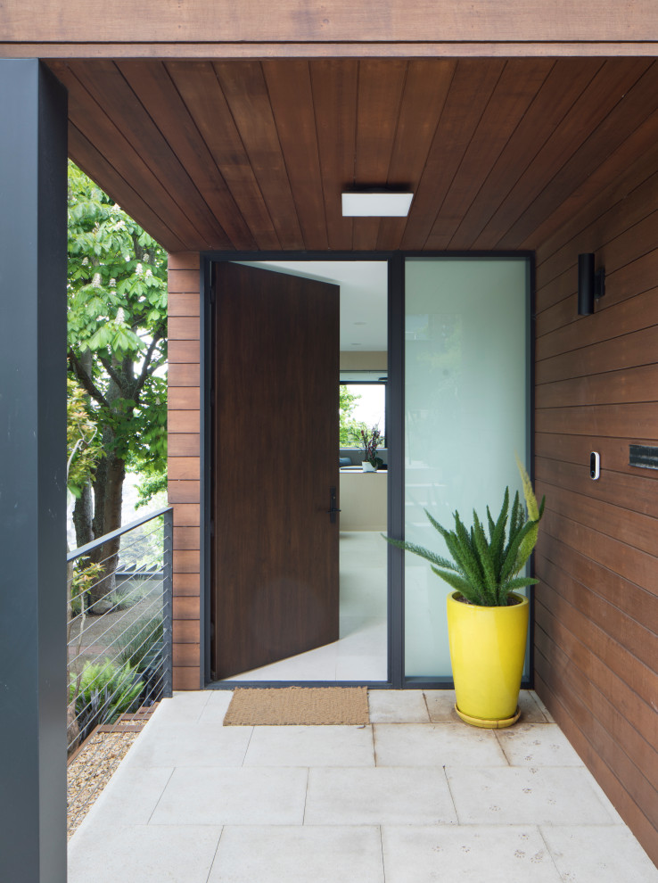 Пример оригинального дизайна: большая входная дверь в стиле модернизм с полом из известняка, одностворчатой входной дверью, входной дверью из дерева среднего тона, белым полом, деревянным потолком и деревянными стенами