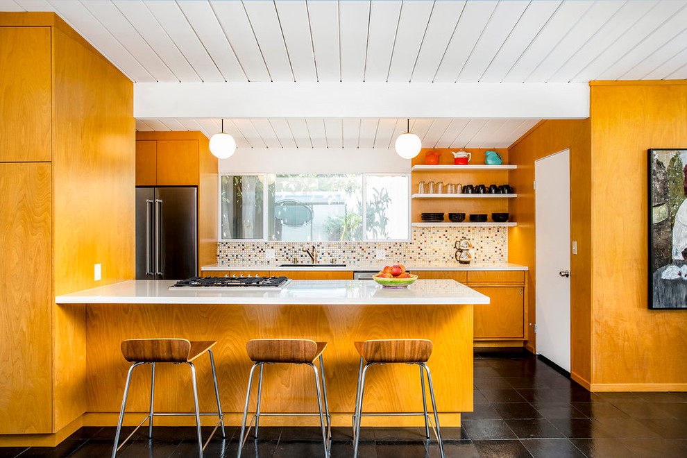 Inspiration for a mid-sized midcentury galley open plan kitchen in Los Angeles with an undermount sink, flat-panel cabinets, multi-coloured splashback, stainless steel appliances, a peninsula, black floor, white benchtop, medium wood cabinets, mosaic tile splashback, slate floors and quartz benchtops.