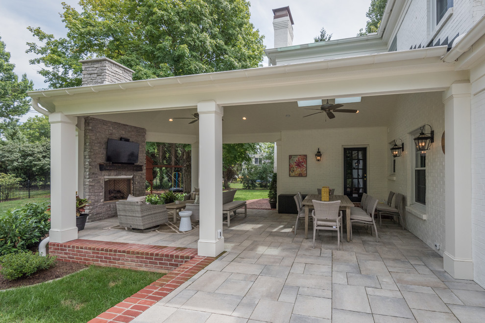 Mid-sized transitional backyard verandah in Louisville with with fireplace, natural stone pavers and a roof extension.