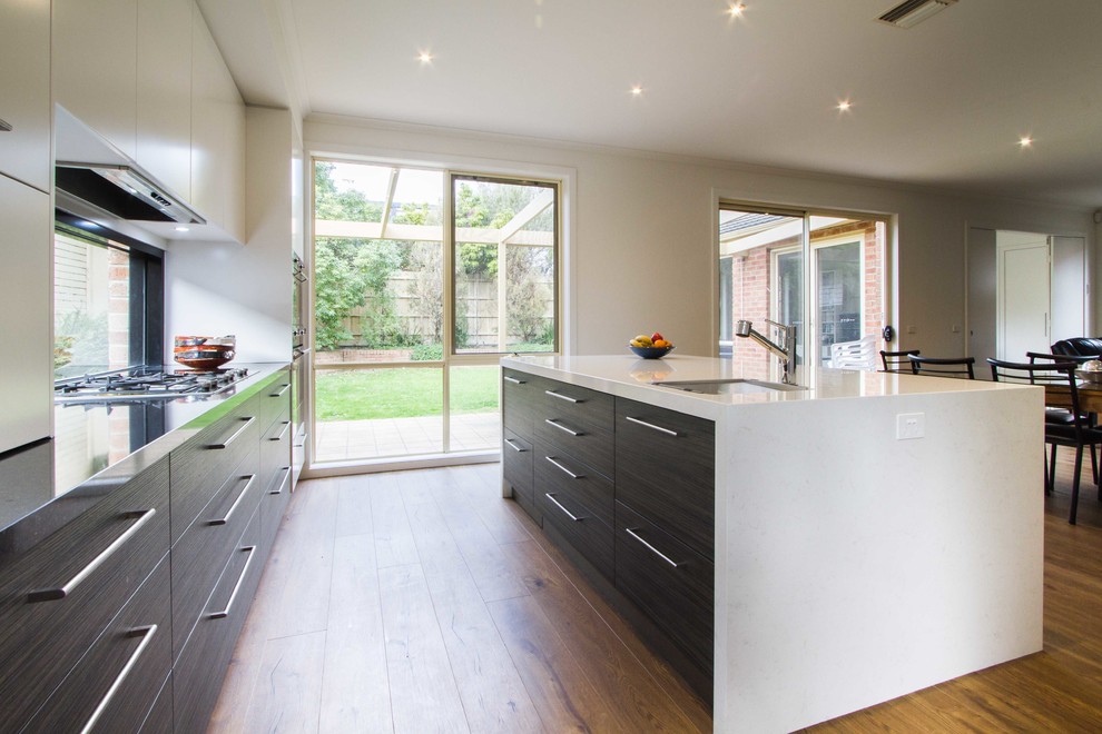 This is an example of an expansive modern l-shaped open plan kitchen in Melbourne with an undermount sink, flat-panel cabinets, quartz benchtops, medium hardwood floors and with island.