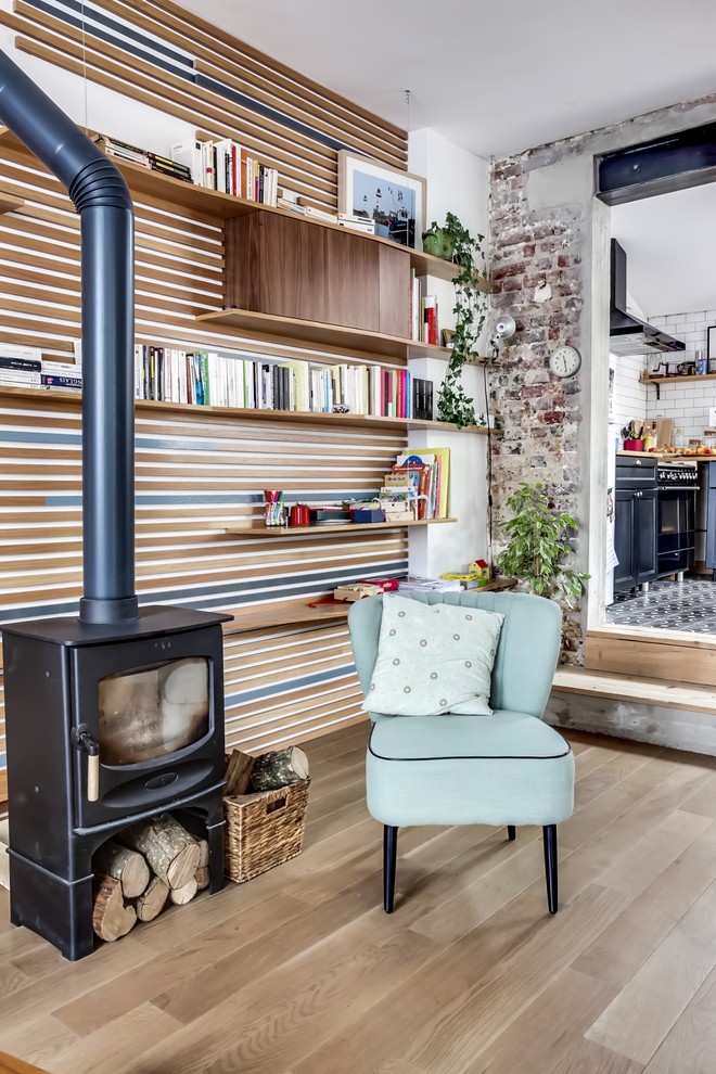 Design ideas for a mid-sized country enclosed living room in Paris with a library, multi-coloured walls, light hardwood floors, a wood stove and no tv.