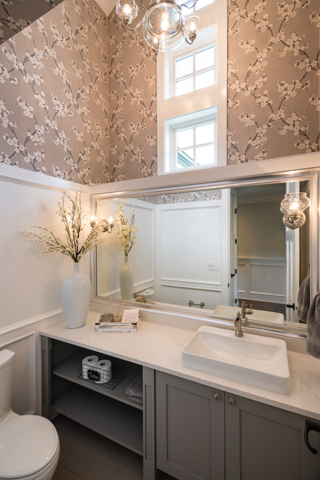 This is an example of a mid-sized transitional powder room in Vancouver with shaker cabinets, grey cabinets, a two-piece toilet, multi-coloured walls, medium hardwood floors, a vessel sink and engineered quartz benchtops.