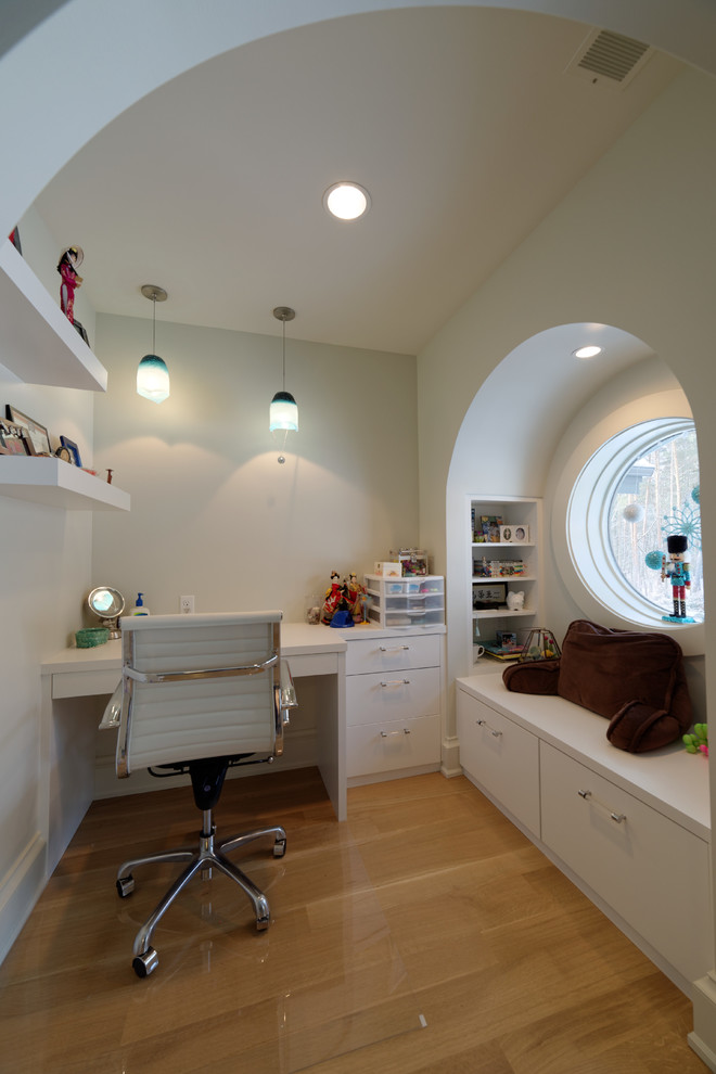 This is an example of a mid-sized arts and crafts gender-neutral kids' study room for kids 4-10 years old in Detroit with white walls, light hardwood floors and beige floor.