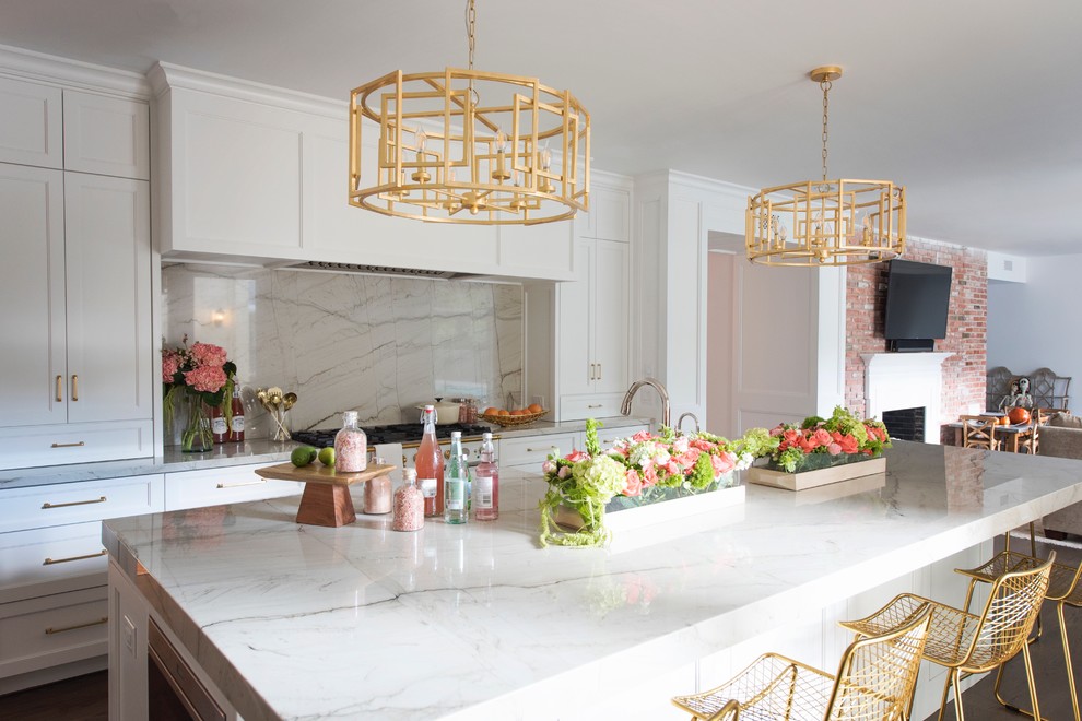 Large transitional l-shaped medium tone wood floor and brown floor open concept kitchen photo with a farmhouse sink, recessed-panel cabinets, white cabinets, quartzite countertops, white backsplash, stone slab backsplash, paneled appliances and an island