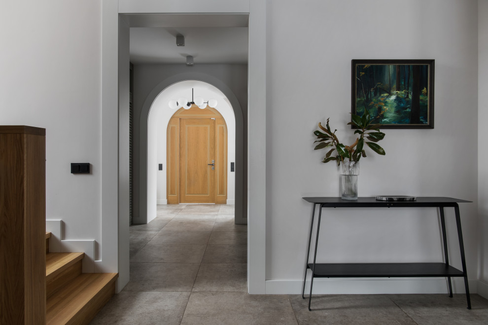 Стильный дизайн: большая входная дверь: освещение в современном стиле с серыми стенами, полом из керамогранита, одностворчатой входной дверью, входной дверью из светлого дерева и серым полом - последний тренд