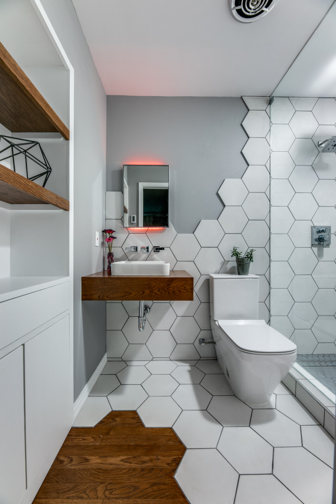 Inspiration for a small contemporary 3/4 bathroom in Dallas with grey cabinets, an open shower, a one-piece toilet, white tile, ceramic tile, grey walls, medium hardwood floors, wood benchtops, brown floor, a hinged shower door, brown benchtops, a single vanity and a floating vanity.