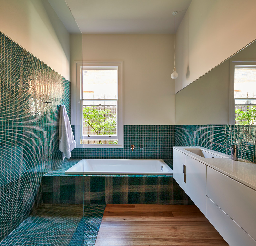 Contemporary bathroom in Melbourne with flat-panel cabinets, white cabinets, a drop-in tub, a curbless shower, blue tile, green tile, mosaic tile, an undermount sink, medium hardwood floors, turquoise floor and an open shower.