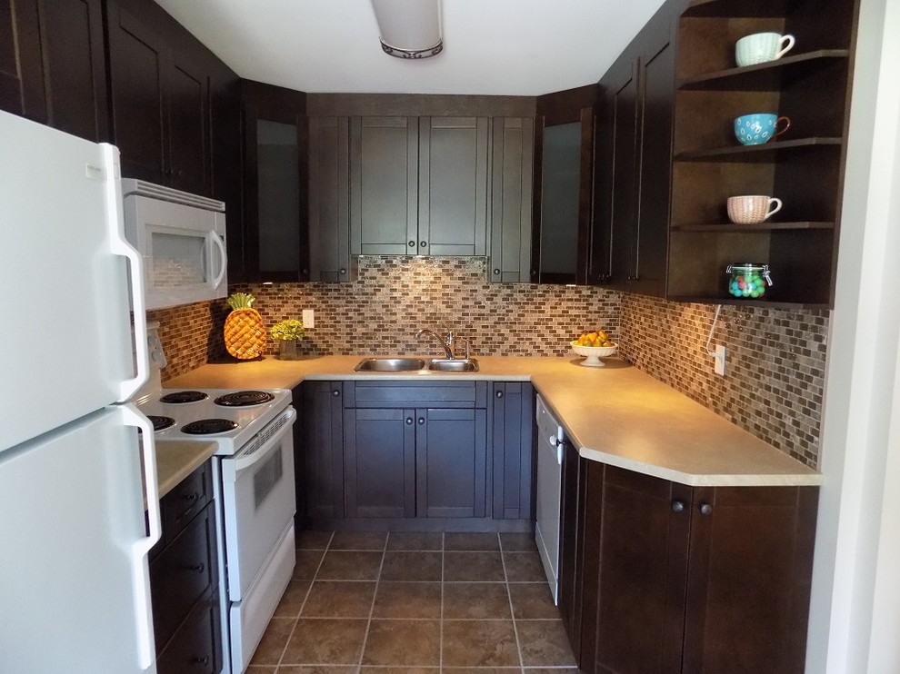 Small transitional u-shaped kitchen in Ottawa with a double-bowl sink, beaded inset cabinets, dark wood cabinets, granite benchtops, beige splashback, glass tile splashback, white appliances, ceramic floors, no island, brown floor and beige benchtop.