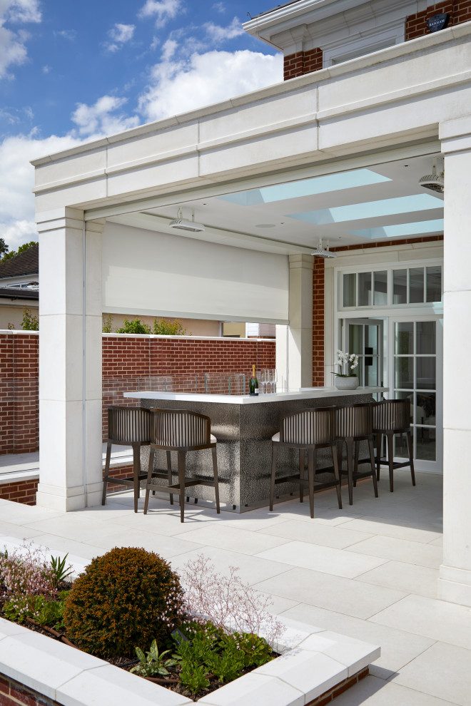 Expansive modern back patio in Hertfordshire with a bar area, natural stone paving and a roof extension.