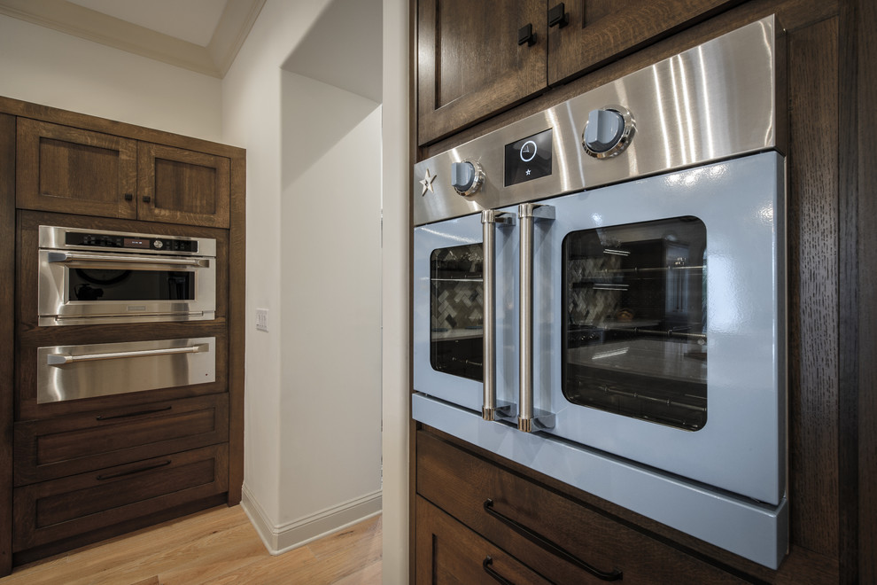 Large transitional galley light wood floor home design photo in Jacksonville with a double-bowl sink, shaker cabinets, dark wood cabinets, quartz countertops, brown backsplash, ceramic backsplash, colored appliances and two islands