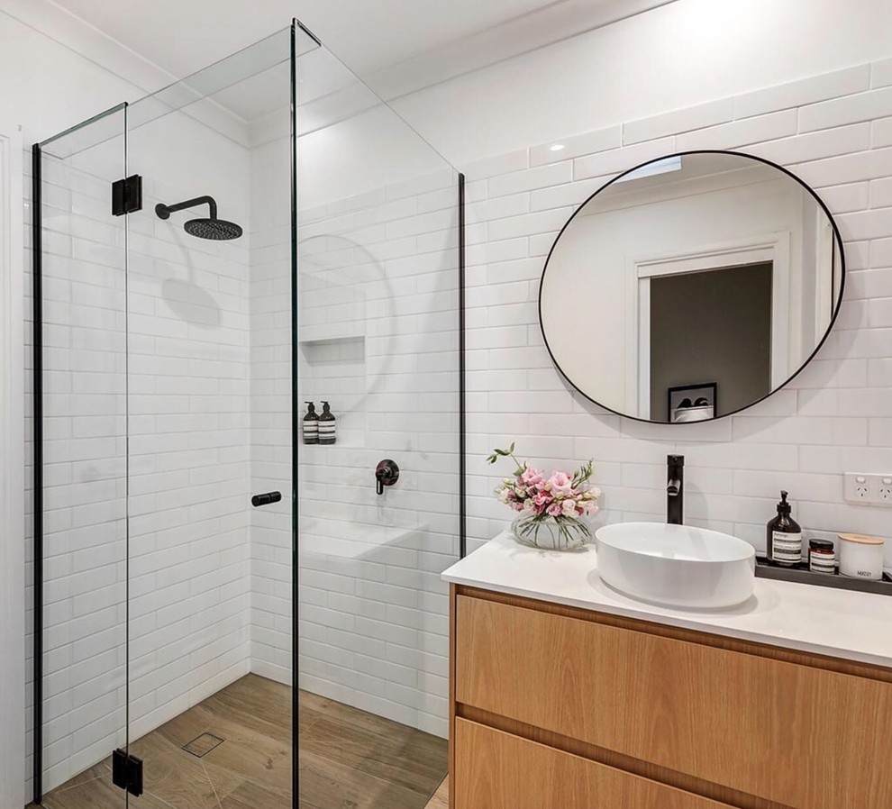 Photo of a mid-sized contemporary master bathroom in Melbourne with light wood cabinets, a corner shower, white tile, ceramic tile, white walls, ceramic floors, a vessel sink, engineered quartz benchtops, brown floor, a hinged shower door and white benchtops.