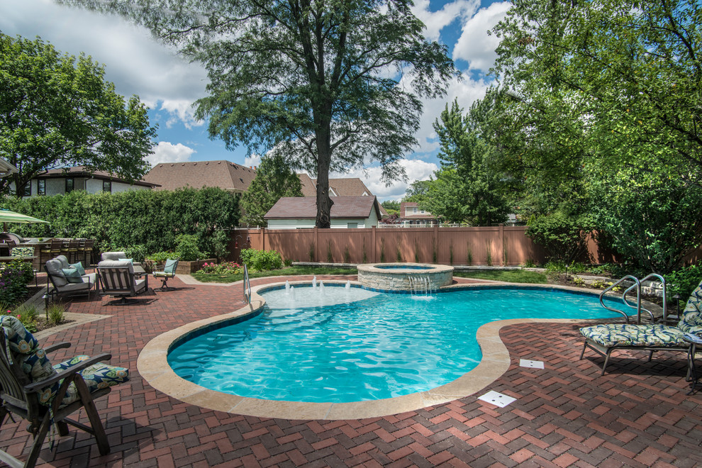 Example of a mid-sized classic backyard brick and custom-shaped pool design in Chicago