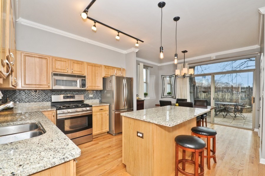 Eat-in kitchen - mid-sized transitional l-shaped light wood floor eat-in kitchen idea in Chicago with an undermount sink, recessed-panel cabinets, light wood cabinets, granite countertops, gray backsplash, glass tile backsplash, stainless steel appliances and an island
