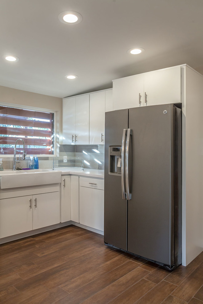 Example of a transitional u-shaped porcelain tile open concept kitchen design in Phoenix with shaker cabinets, white cabinets, quartz countertops, multicolored backsplash, porcelain backsplash, an island, a farmhouse sink and stainless steel appliances