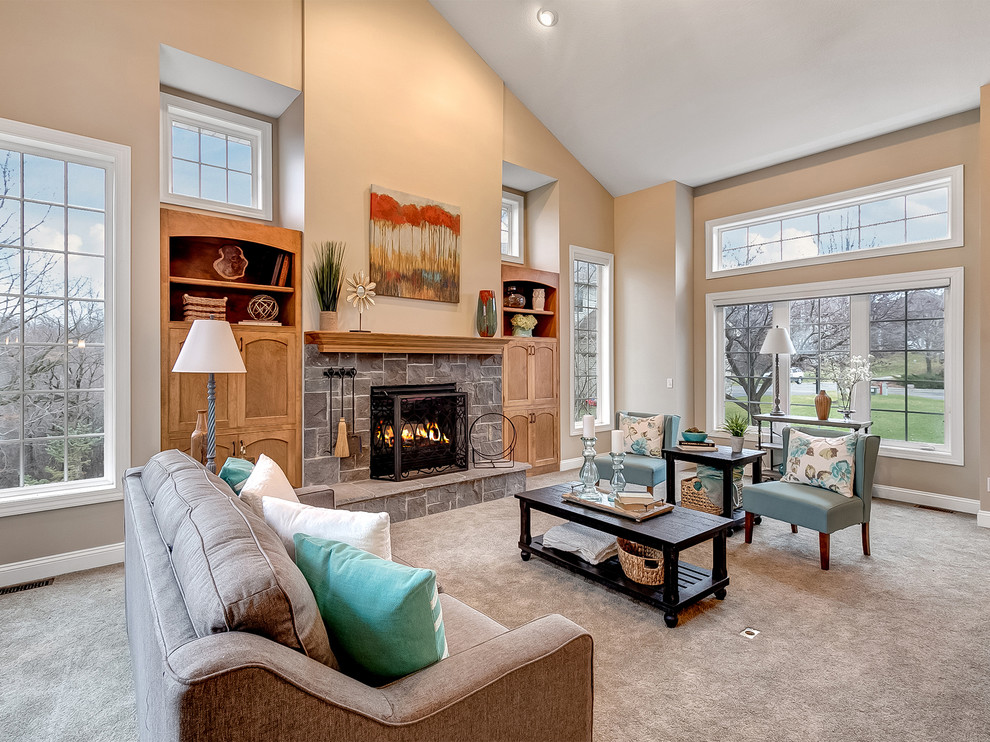 This is an example of a traditional formal open concept living room in Minneapolis with brown walls, carpet, a standard fireplace, a stone fireplace surround and grey floor.