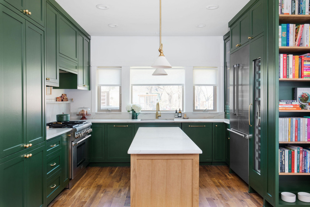 Example of a mid-sized transitional u-shaped medium tone wood floor and brown floor open concept kitchen design in Austin with an undermount sink, shaker cabinets, green cabinets, quartzite countertops, white backsplash, stone slab backsplash, stainless steel appliances, an island and white countertops