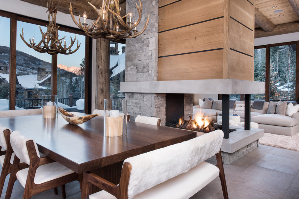 Inspiration for a mid-sized contemporary open plan dining in Denver with beige walls, slate floors, a two-sided fireplace, a stone fireplace surround and grey floor.