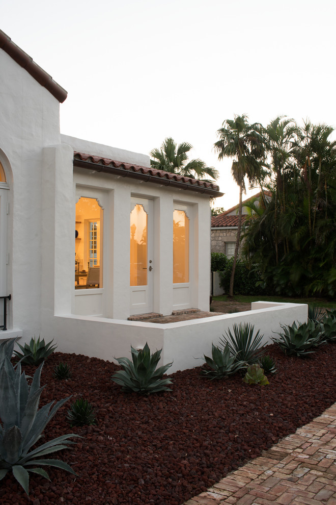 Photo of a mediterranean two-storey white house exterior in Miami with a flat roof and a tile roof.