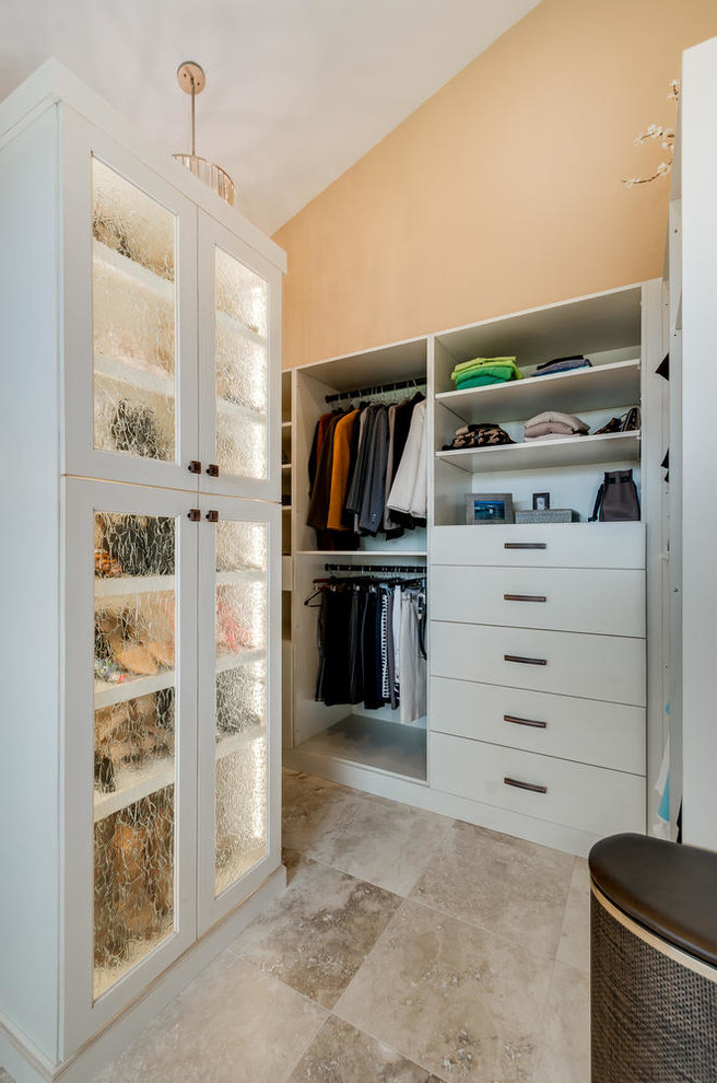 Large mediterranean storage and wardrobe in Denver with glass-front cabinets, beige cabinets, travertine floors and beige floor.