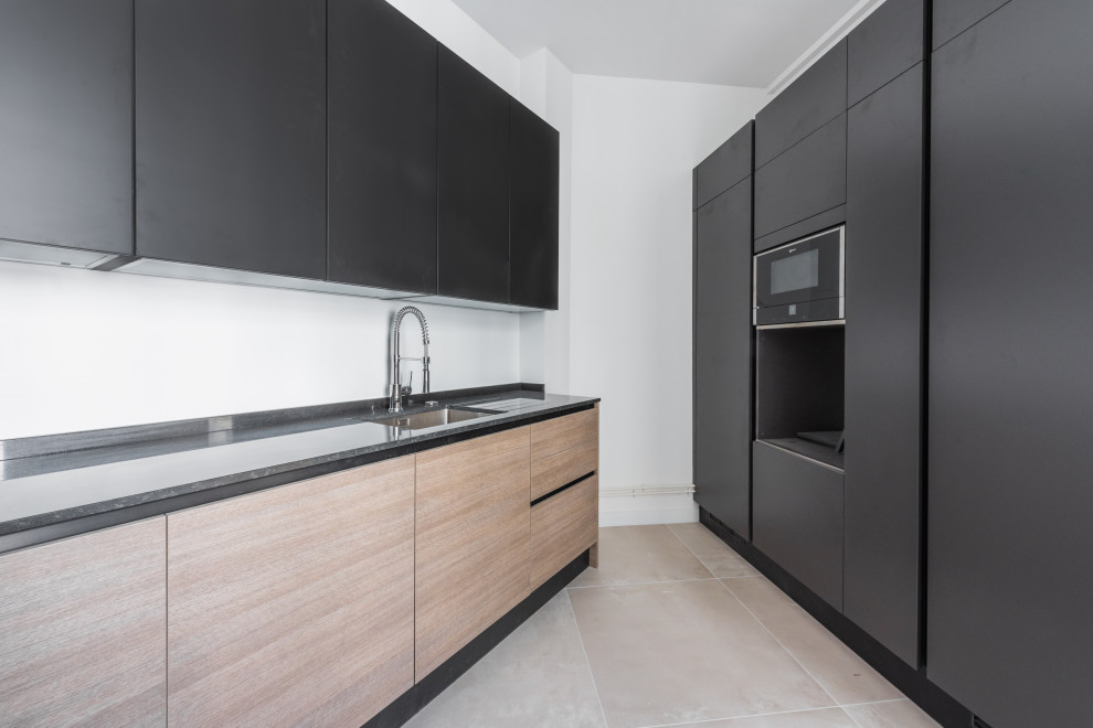 Photo of an expansive contemporary l-shaped separate kitchen in Paris with an undermount sink, beaded inset cabinets, black cabinets, granite benchtops, white splashback, panelled appliances, ceramic floors, no island, black benchtop and beige floor.