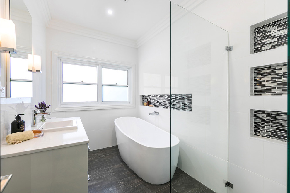Large contemporary kids bathroom in Sydney with flat-panel cabinets, grey cabinets, a freestanding tub, a double shower, a one-piece toilet, white tile, ceramic tile, white walls, porcelain floors, a drop-in sink, engineered quartz benchtops, grey floor and a hinged shower door.