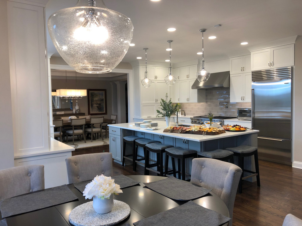 Huge transitional u-shaped dark wood floor and brown floor eat-in kitchen photo in Cincinnati with an undermount sink, recessed-panel cabinets, white cabinets, quartz countertops, beige backsplash, subway tile backsplash, stainless steel appliances, an island and white countertops
