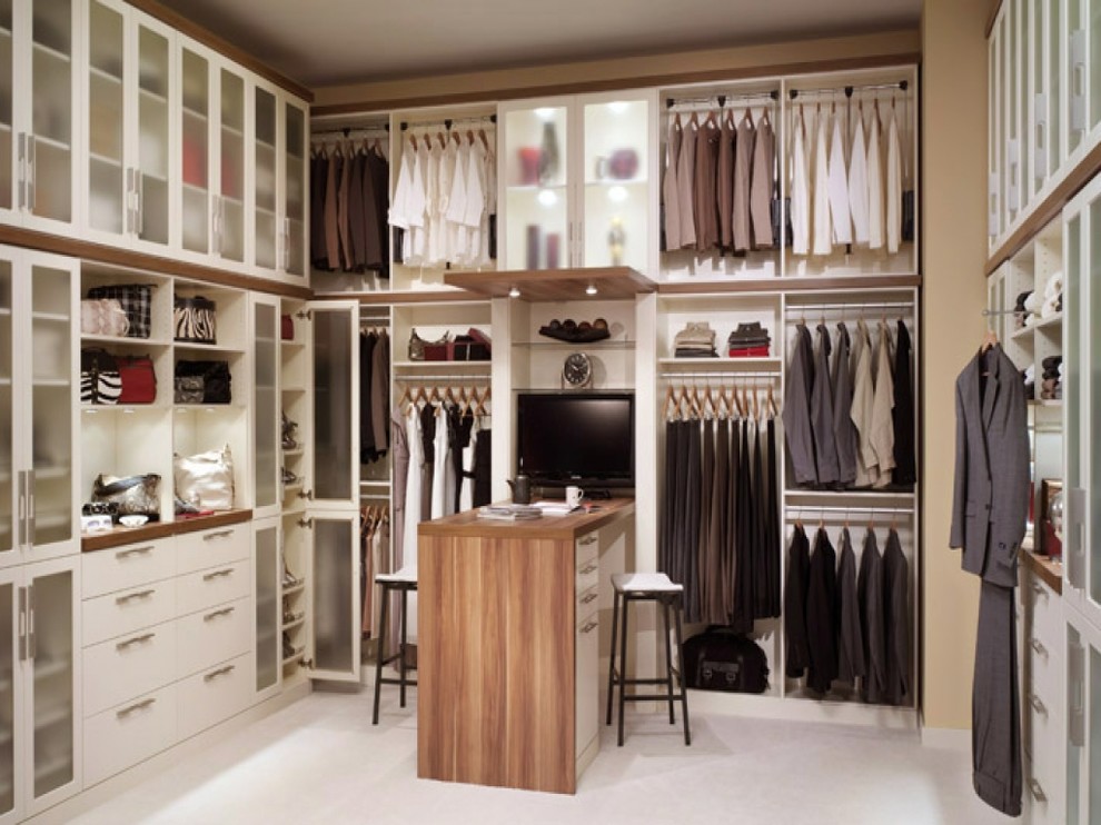 Photo of a large transitional gender-neutral dressing room in DC Metro with glass-front cabinets, white cabinets, carpet and beige floor.