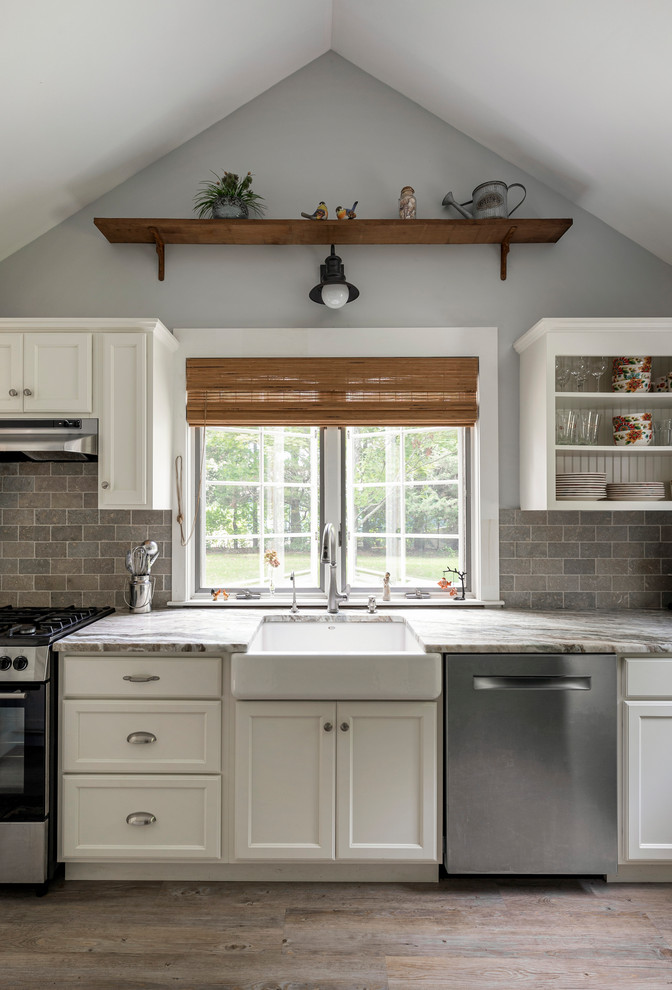 Photo of a beach style kitchen in Providence with a farmhouse sink, recessed-panel cabinets, quartzite benchtops, limestone splashback and stainless steel appliances.