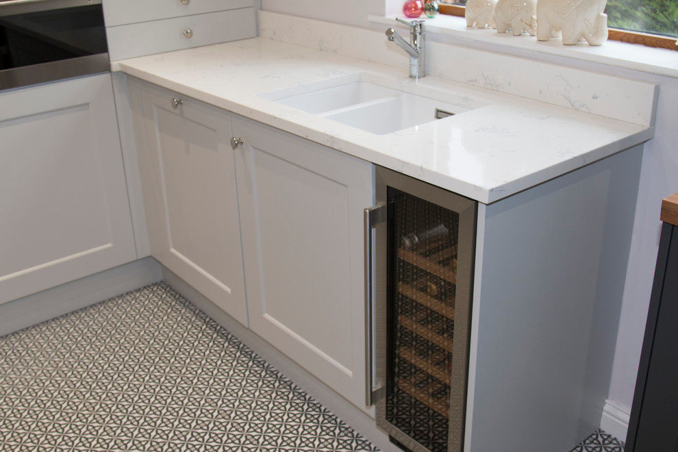 Small traditional u-shaped enclosed kitchen in Belfast with a submerged sink, recessed-panel cabinets, grey cabinets, quartz worktops, white splashback, stone slab splashback, stainless steel appliances, ceramic flooring and a breakfast bar.