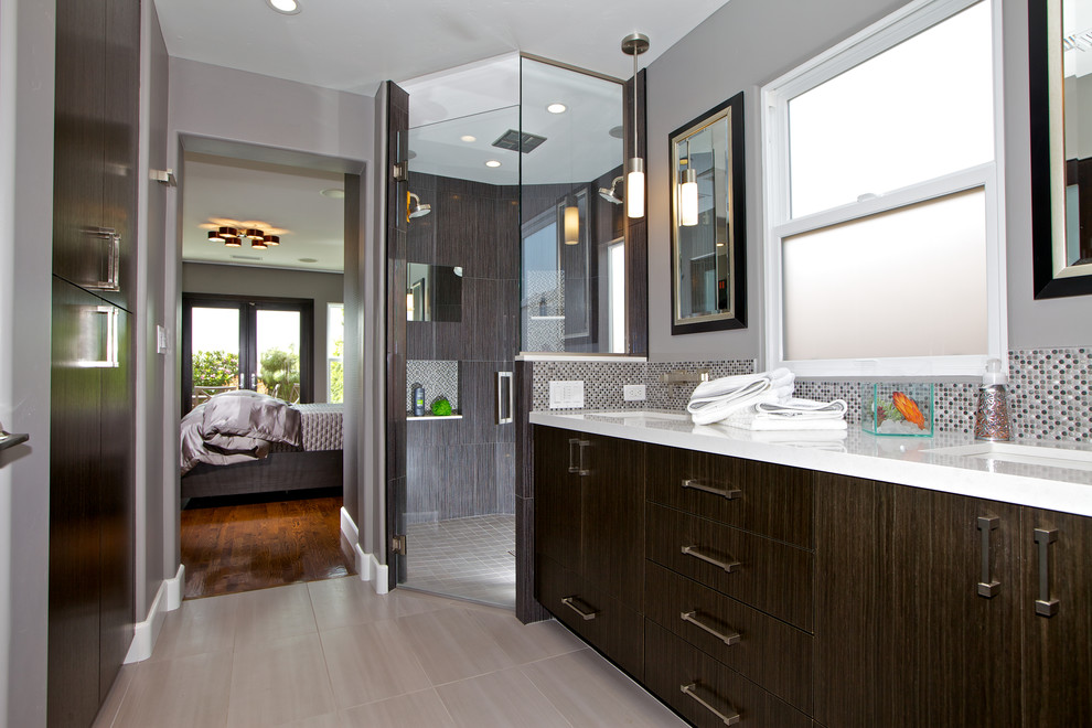 Photo of a mid-sized contemporary master bathroom in San Diego with a curbless shower, an undermount sink, flat-panel cabinets, solid surface benchtops, multi-coloured tile, mosaic tile, dark wood cabinets, grey walls, porcelain floors, grey floor, a hinged shower door and white benchtops.