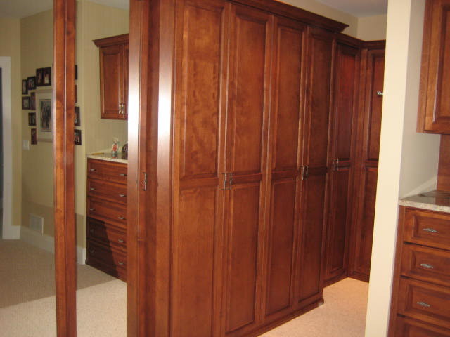 This is an example of a large traditional gender-neutral walk-in wardrobe in Chicago with raised-panel cabinets, medium wood cabinets and carpet.