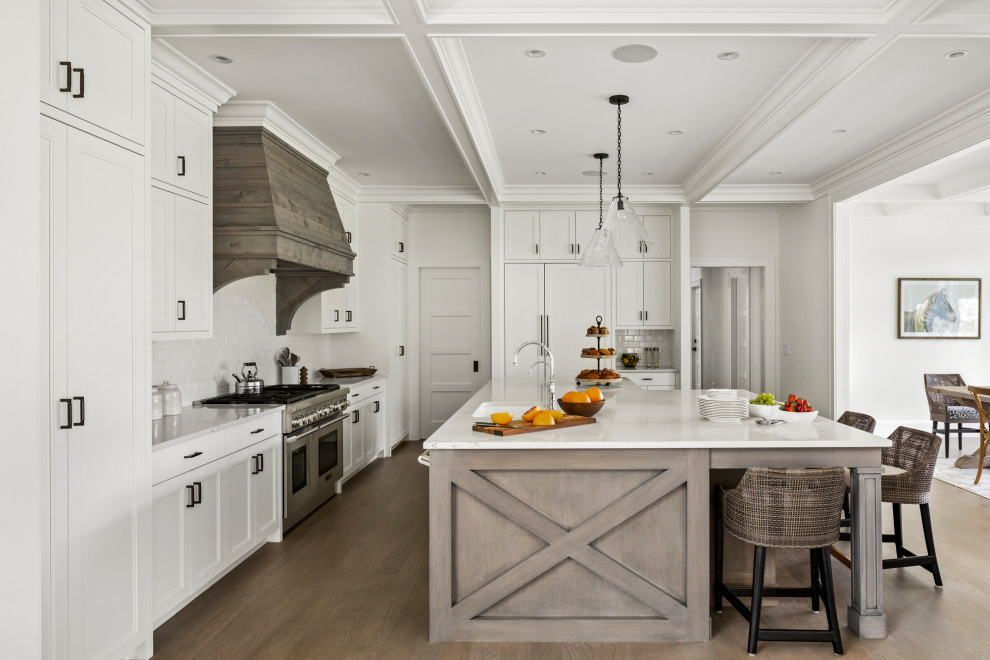 Photo of a large country l-shaped open plan kitchen in Boston with an undermount sink, white cabinets, marble benchtops, white splashback, subway tile splashback, stainless steel appliances, with island, white benchtop, shaker cabinets, medium hardwood floors and coffered.