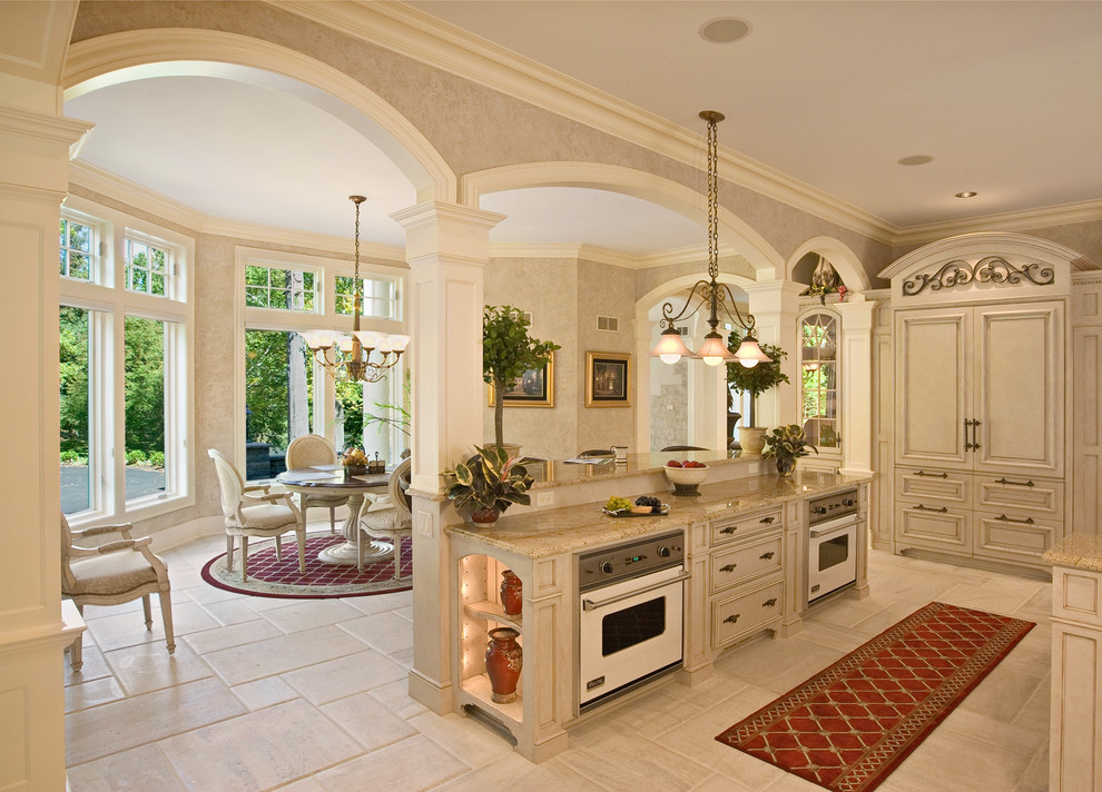 This is an example of a large mediterranean l-shaped eat-in kitchen in Philadelphia with an undermount sink, beaded inset cabinets, beige cabinets, granite benchtops, beige splashback, ceramic splashback, panelled appliances, porcelain floors, with island and white floor.