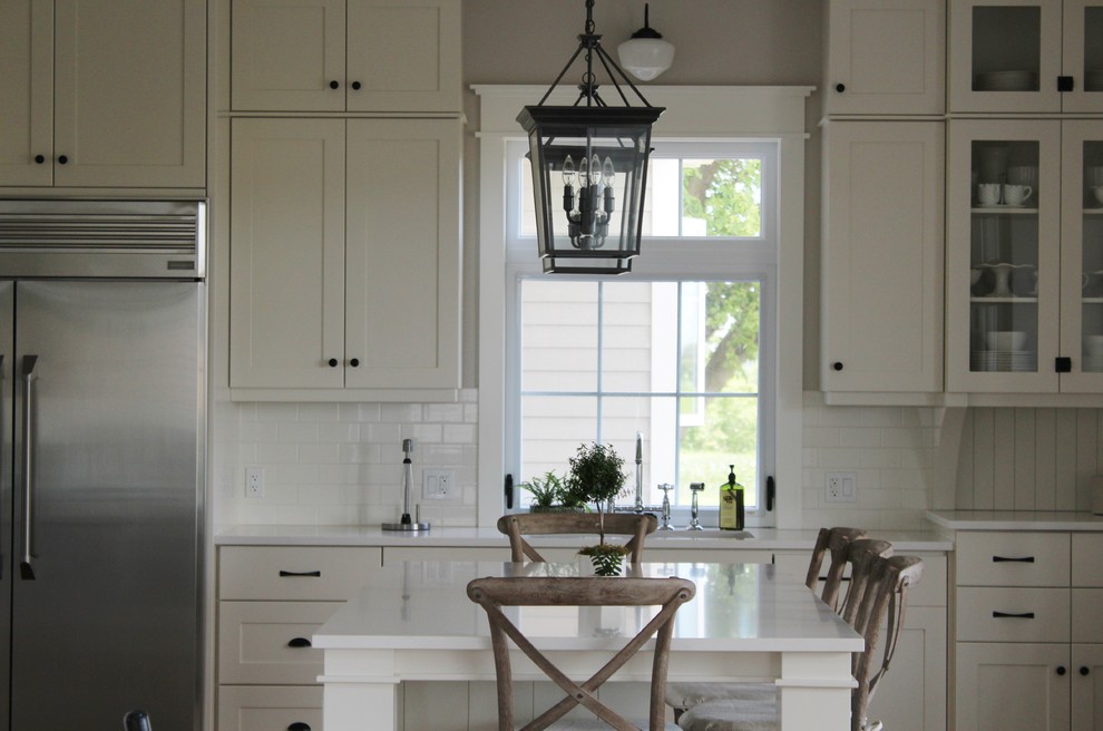 Example of a large transitional l-shaped eat-in kitchen design in Toronto with an undermount sink, shaker cabinets, white cabinets, quartz countertops, white backsplash, stainless steel appliances and an island