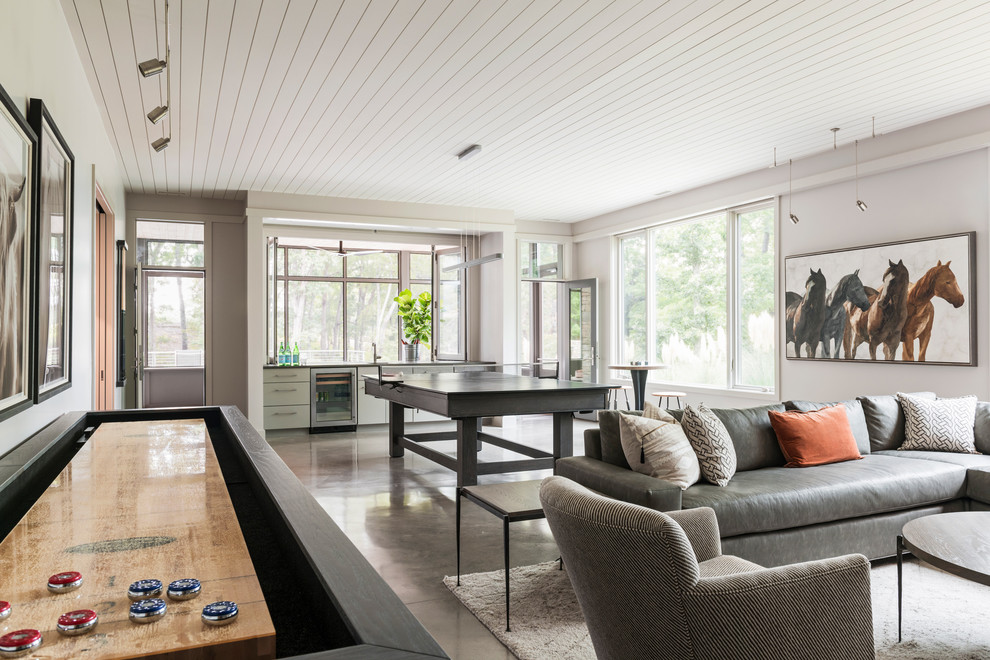 This is an example of a large country open concept family room in Charlotte with white walls, concrete floors, a built-in media wall and grey floor.