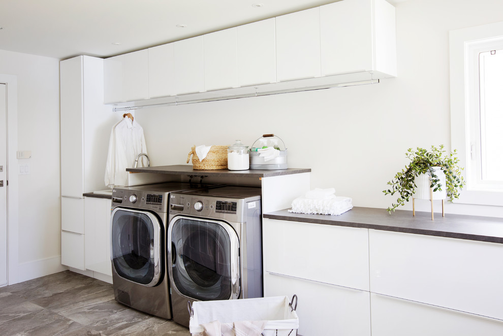 Inspiration for a contemporary galley utility room in Vancouver with a drop-in sink, flat-panel cabinets, white cabinets, laminate benchtops, white walls, porcelain floors, a side-by-side washer and dryer and grey floor.