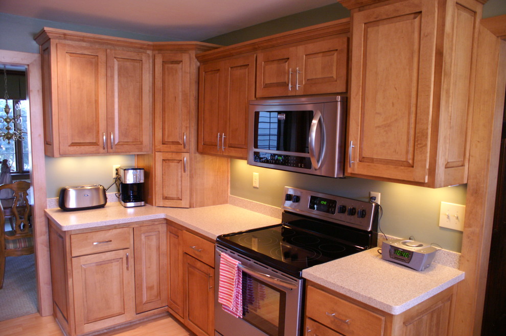Photo of a mid-sized traditional galley separate kitchen in Milwaukee with an undermount sink, raised-panel cabinets, stainless steel appliances, laminate floors, no island, light wood cabinets and terrazzo benchtops.