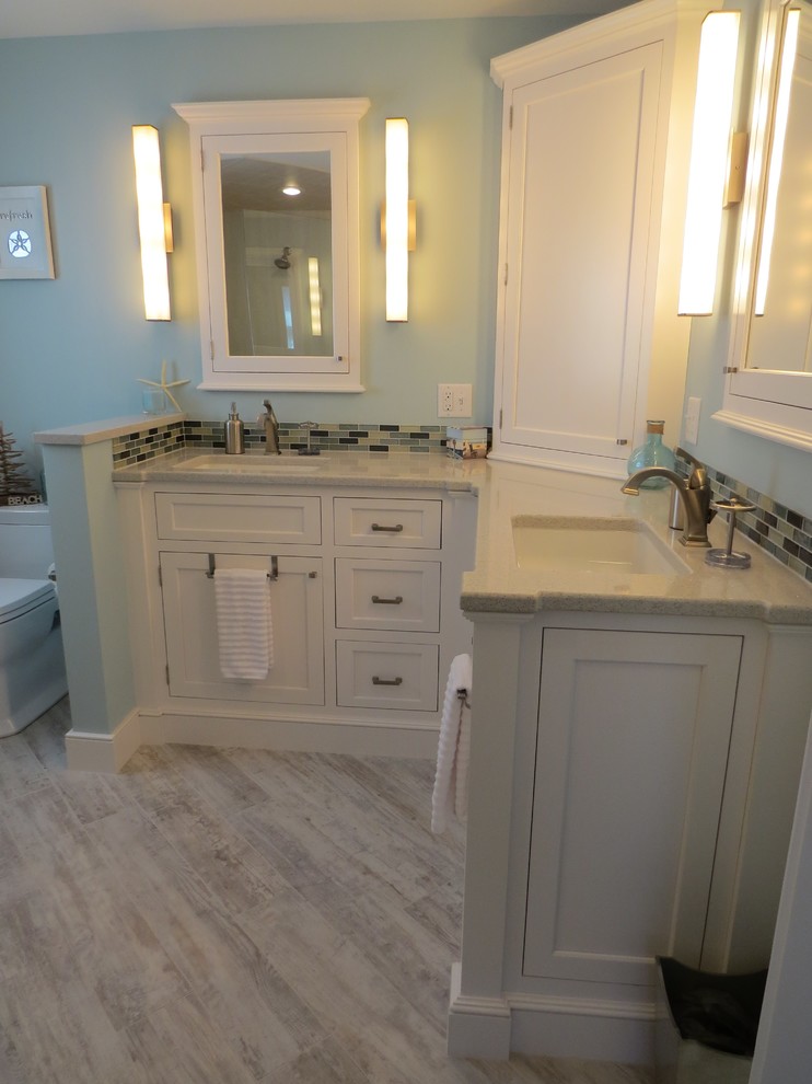 This is an example of a mid-sized beach style master bathroom in Portland Maine with an undermount sink, beaded inset cabinets, white cabinets, engineered quartz benchtops, a curbless shower, a two-piece toilet, multi-coloured tile, glass tile, blue walls and porcelain floors.
