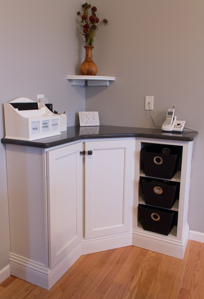 Mid-sized transitional u-shaped medium tone wood floor enclosed kitchen photo with an undermount sink, recessed-panel cabinets, white cabinets, quartz countertops, stainless steel appliances and an island