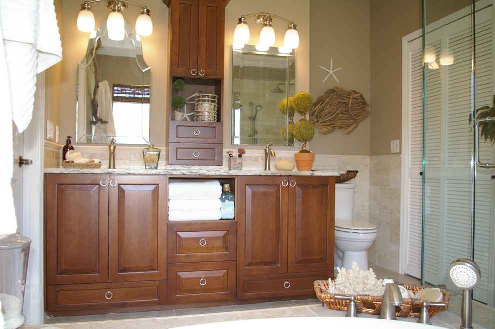 Mid-sized beach style master bathroom in Tampa with open cabinets, medium wood cabinets, a drop-in tub, beige tile, porcelain tile, travertine floors, an undermount sink, granite benchtops, beige walls, a corner shower and a two-piece toilet.