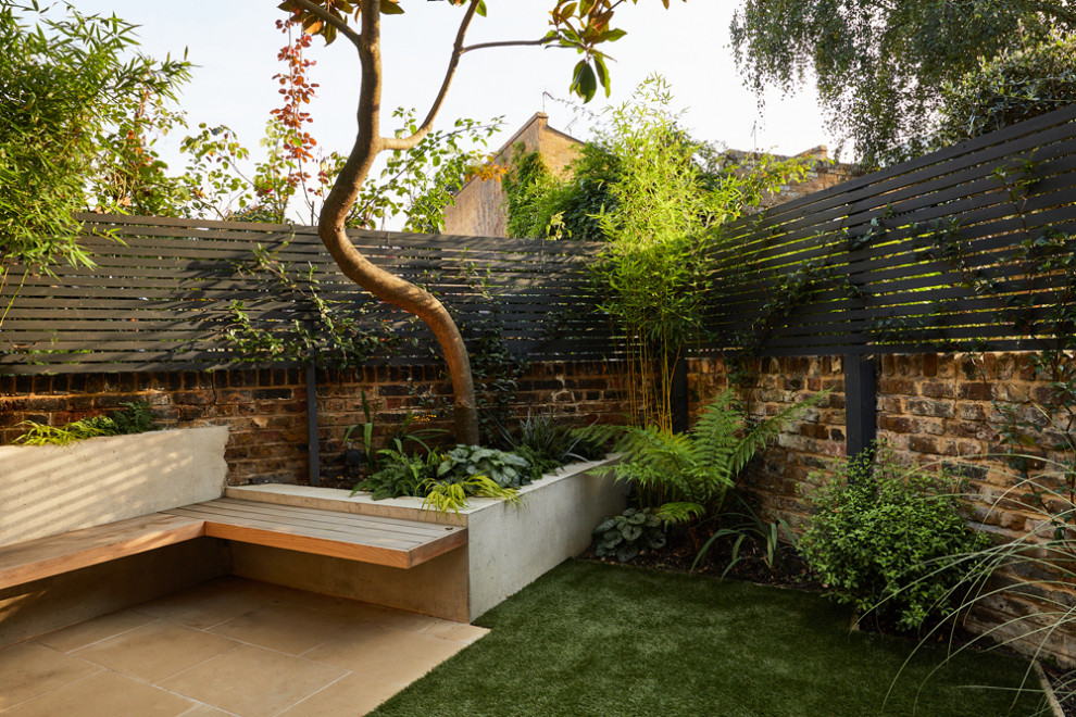 This is an example of a small contemporary back partial sun garden in London with a wood fence.