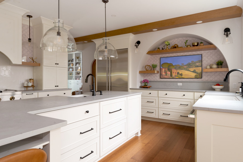 Large medium tone wood floor and exposed beam eat-in kitchen photo with white backsplash, stainless steel appliances and an island