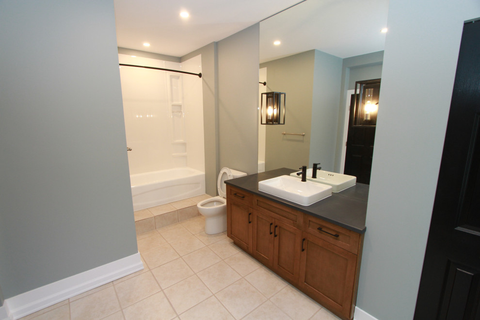 Design ideas for a modern bathroom in Other with shaker cabinets, medium wood cabinets, an alcove tub, a shower/bathtub combo, a one-piece toilet, mirror tile, blue walls, ceramic floors, a trough sink, laminate benchtops, beige floor, a shower curtain, black benchtops, a single vanity and a freestanding vanity.