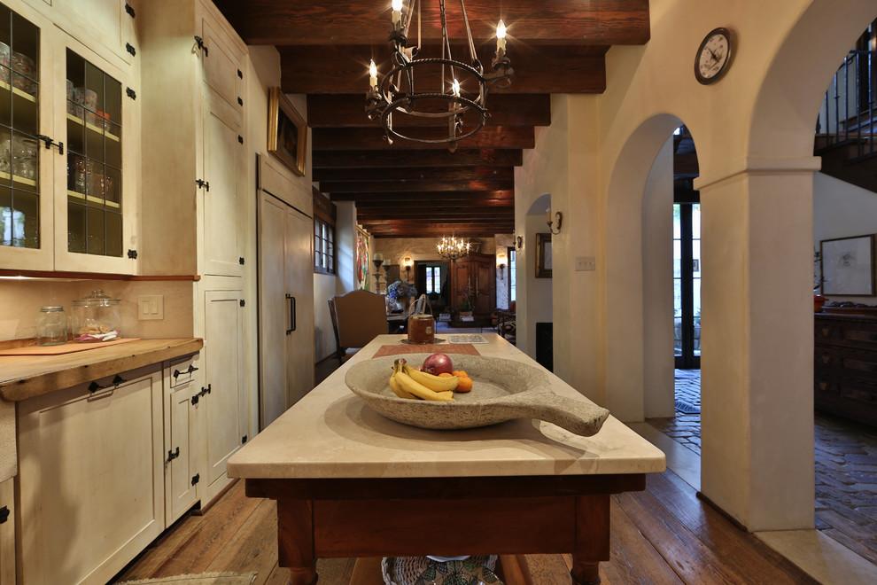 Example of a mid-sized mountain style single-wall medium tone wood floor and brown floor kitchen design in Austin with a farmhouse sink, shaker cabinets, white cabinets, an island, limestone countertops, multicolored backsplash, ceramic backsplash and white appliances